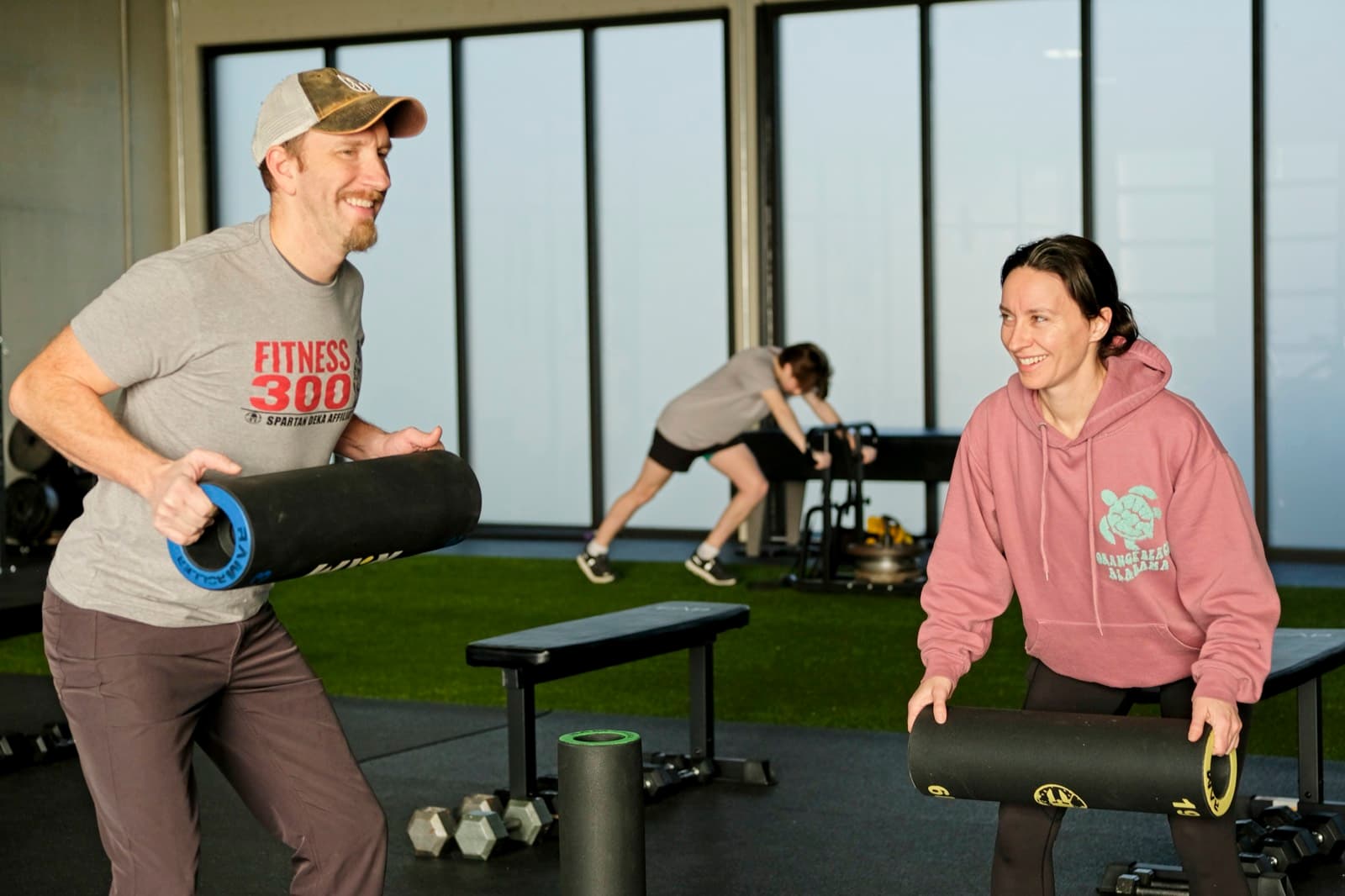 A Fitness 300 coach guiding a member through a movement on the turf