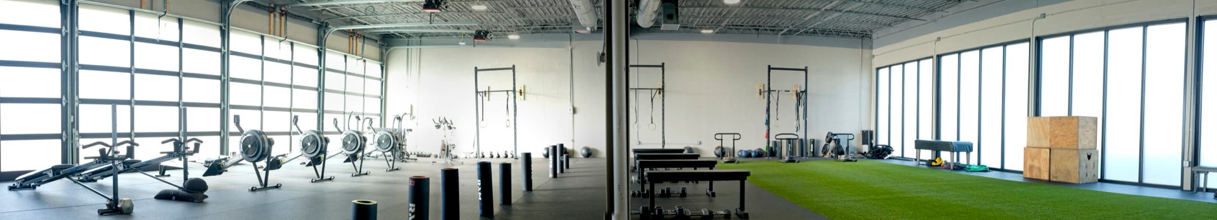 Panorama of the Fitness 300 floor showing rowers, free weights and the turf lane