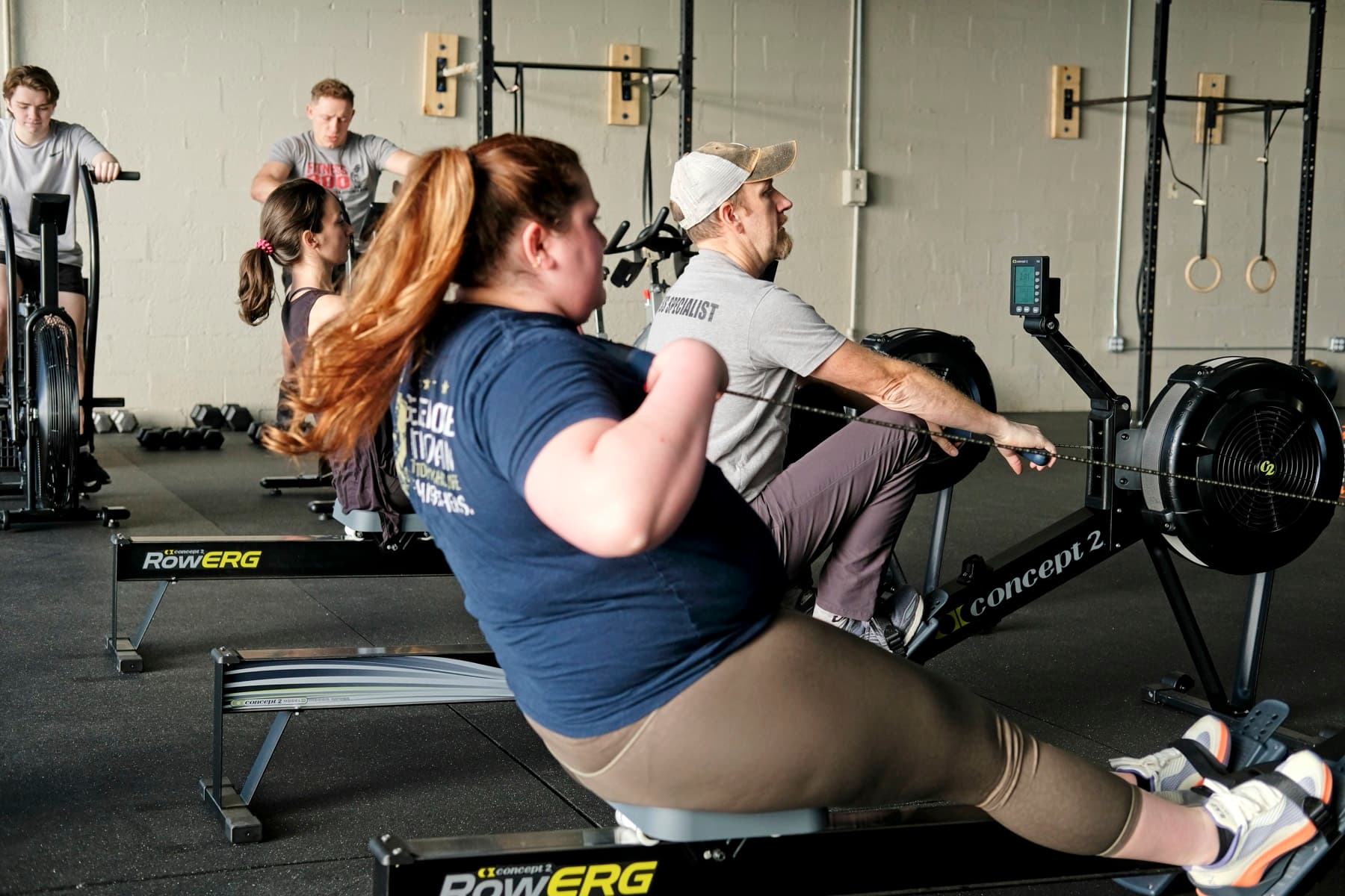 A member training on a Concept2 rower alongside a coach at Fitness 300